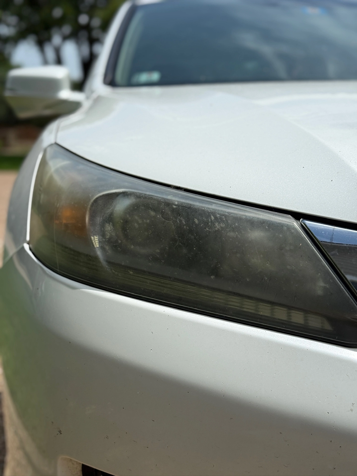Cloudy headlight on a silver sedan before restoration